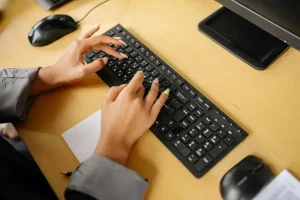 Mãos digitando em um teclado preto